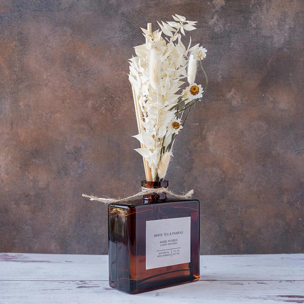 Right angle view of the White Tea & Pampas Bouquet Reed Diffuser on a rustic and white wood background