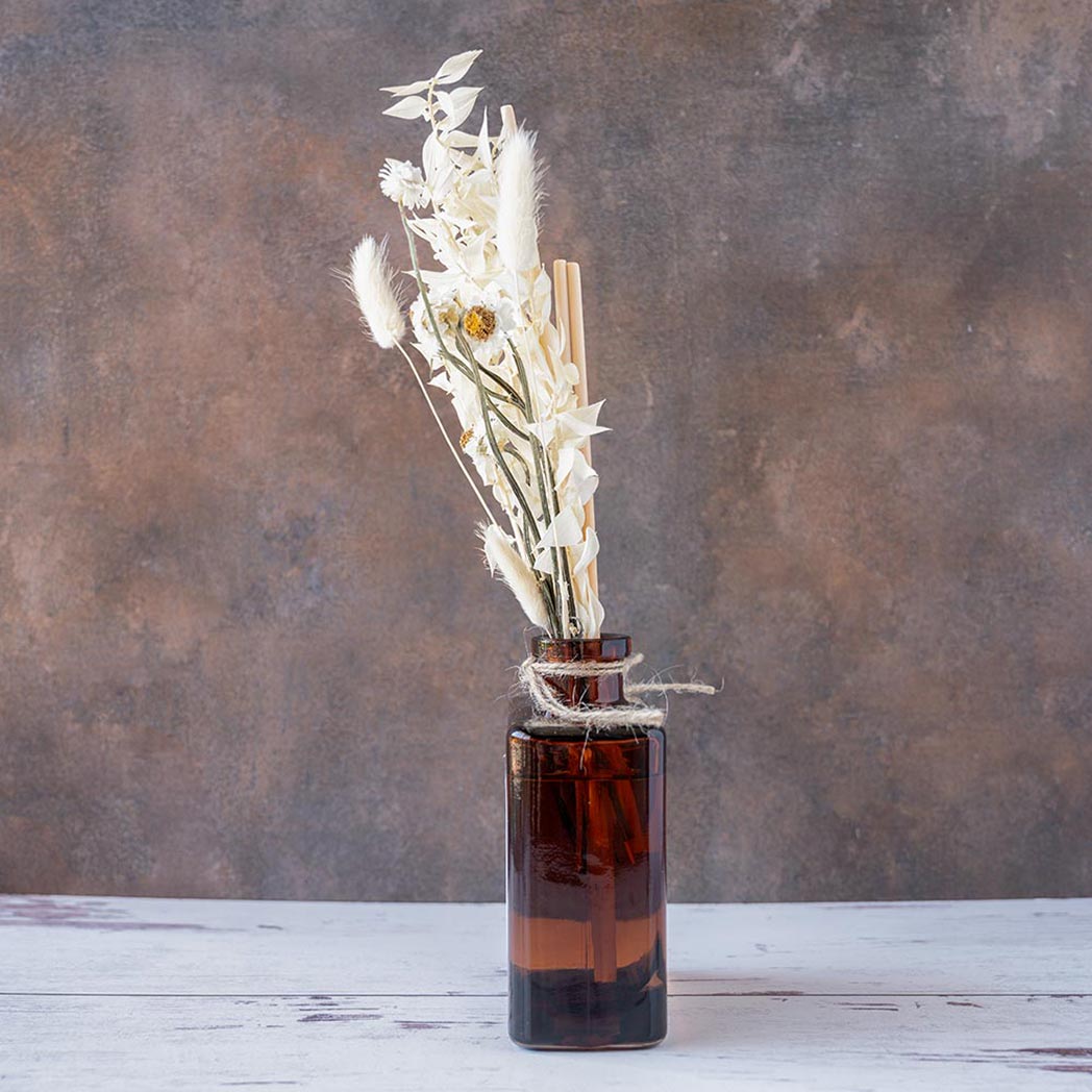 Left side view of the White Tea & Pampas Bouquet Reed Diffuser on a rustic and white wood background