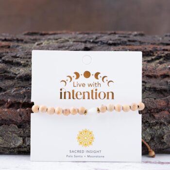 Lunar Wisdom Palo Santo Moonstone Bracelet with Lotus & Luna branded card against a rustic piece of wood