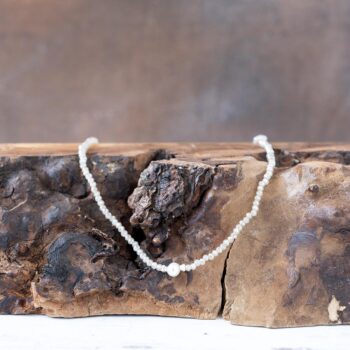 Front view of the Sparkling Shores Crystal Necklace Laying on a Rustic Piece of Wood