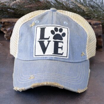 Vintage Life's Love Paws distressed trucker cap in turquoise and against a rustic background