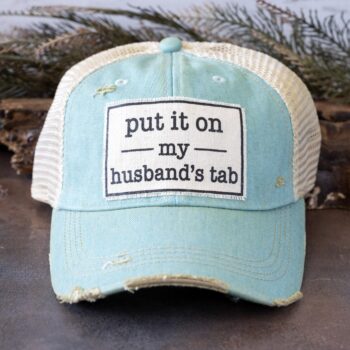 Vintage Life's Put it on my Husband's Tab distressed trucker cap in turquoise and against a rustic background