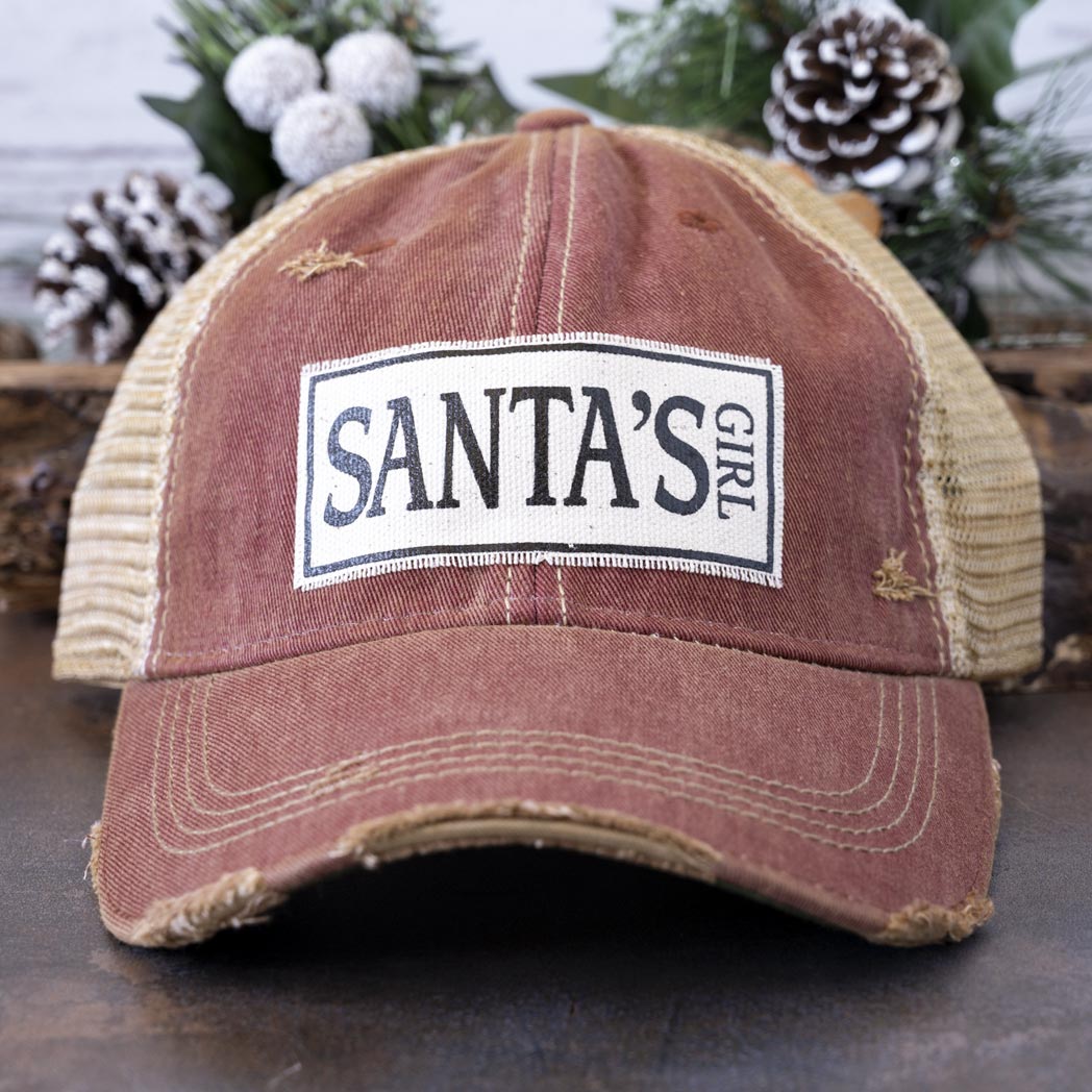 Vintage Life's Santa's Girl distressed trucker cap in turquoise and against a rustic background