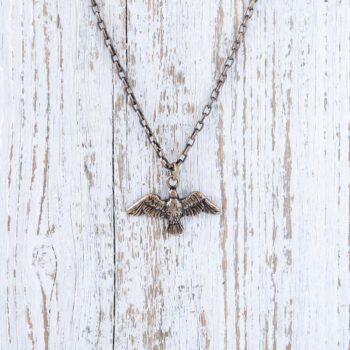 Front view of the Johnny Ltrd Freedom Eagle men's necklace against a rustic white wood background