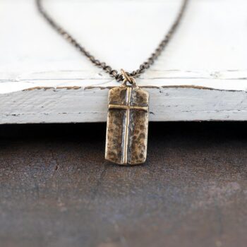 Front view of the Lord's Prayer Cross Necklace against a rustic white wood background