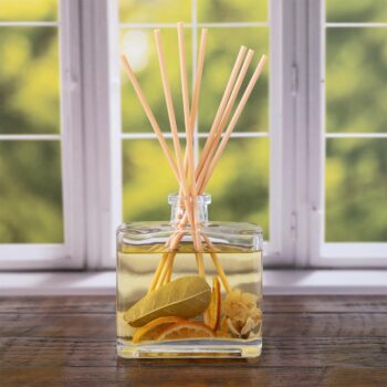 Forbidden Flower Oasis Botanical Reed Diffuser front view on rustic wood and window with greenery