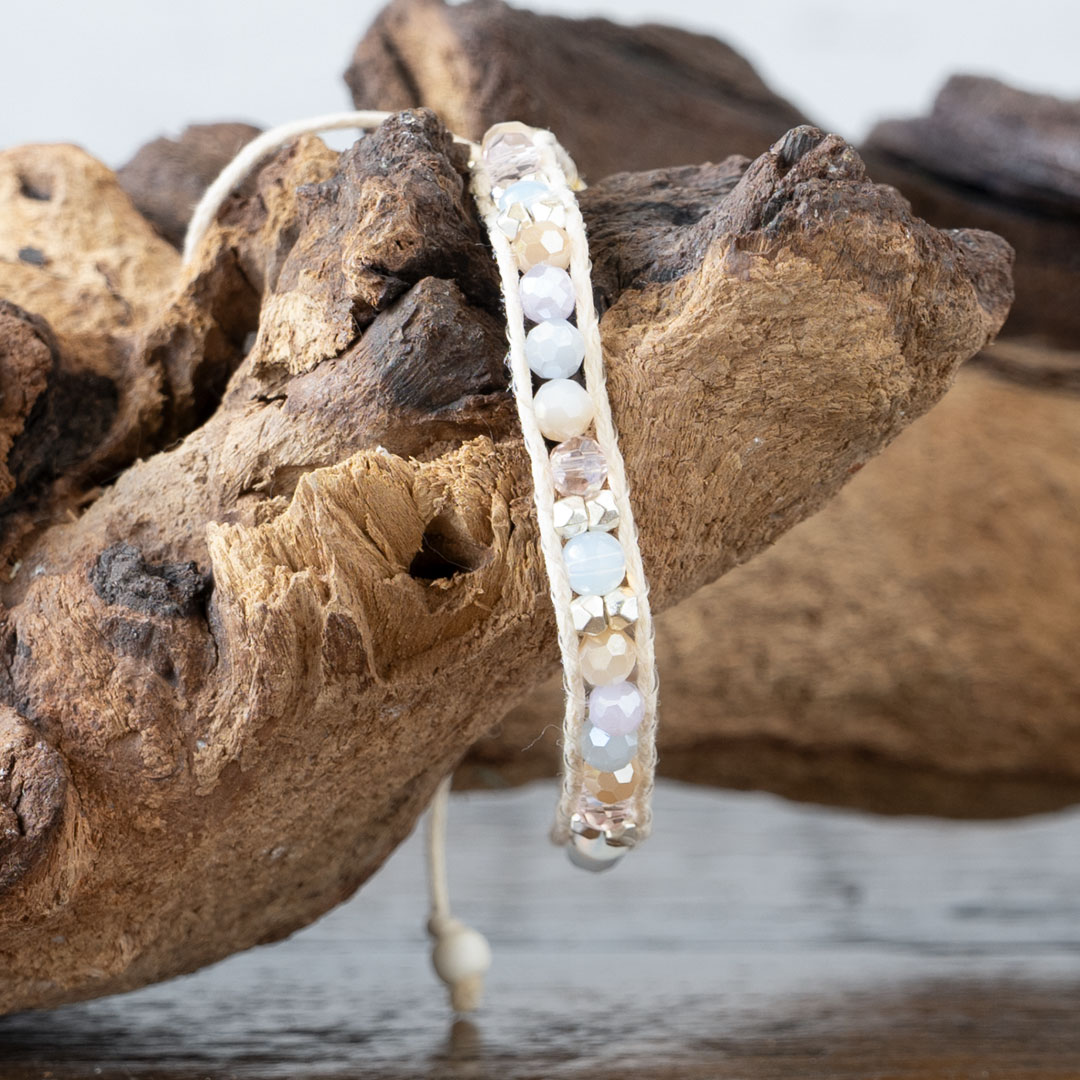 Lotus & Luna Coastal Coral Healing Stones Bracelet dangling from a piece of driftwood