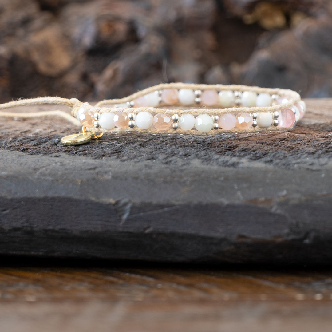 Side view of the Coastal Coral Healing Stones Bracelet by Lotus & Luna on a rustic piece of wood and against rustic wood backdrop