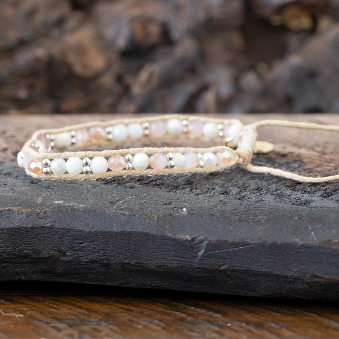 Side view of the Coastal Coral Healing Stones Bracelet by Lotus & Luna on a rustic piece of wood and against rustic wood backdrop