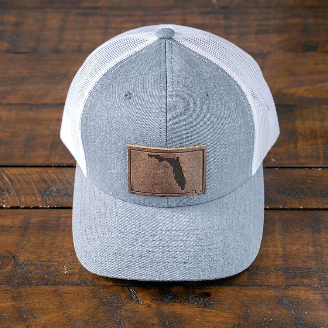 State of Florida leather patch hat in the color heather gray & white by RANGE Leather on a rustic wood tabletop