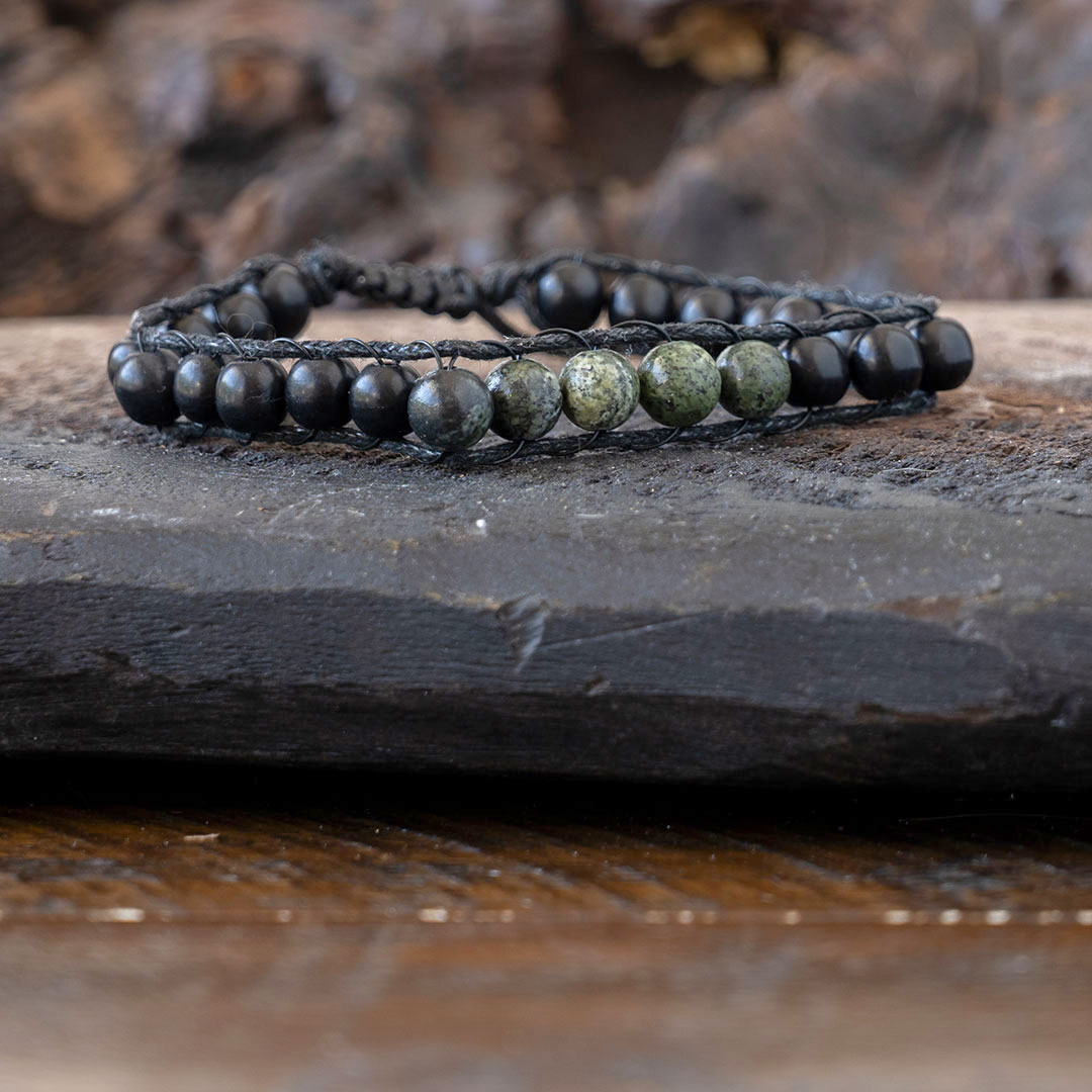 Men's Lotus & Luna Reef Keeper beaded bracelet resting on a piece of driftwood and rustic wood background