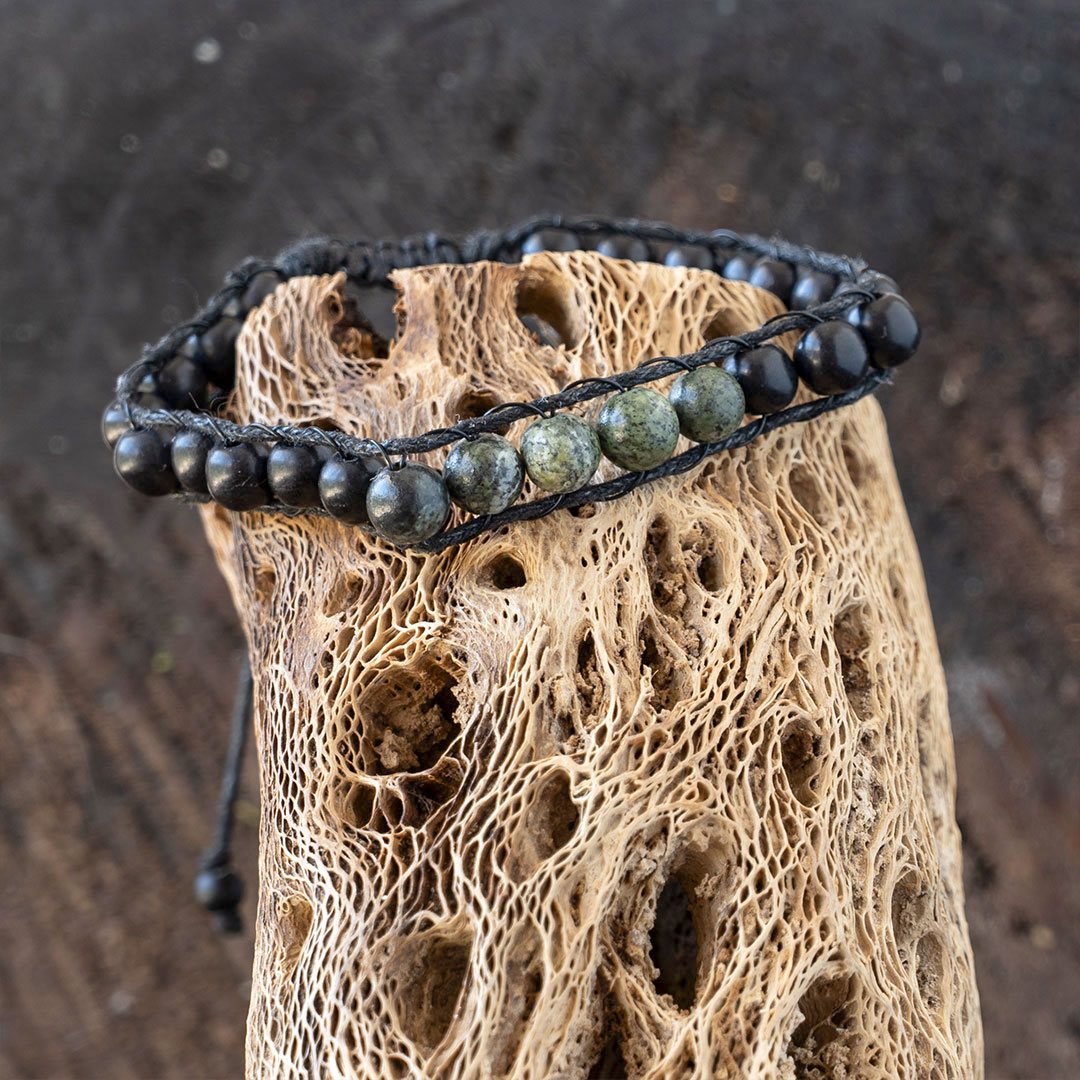 Men's Lotus & Luna Reef Keeper beaded bracelet resting on a piece of driftwood and rustic wood background