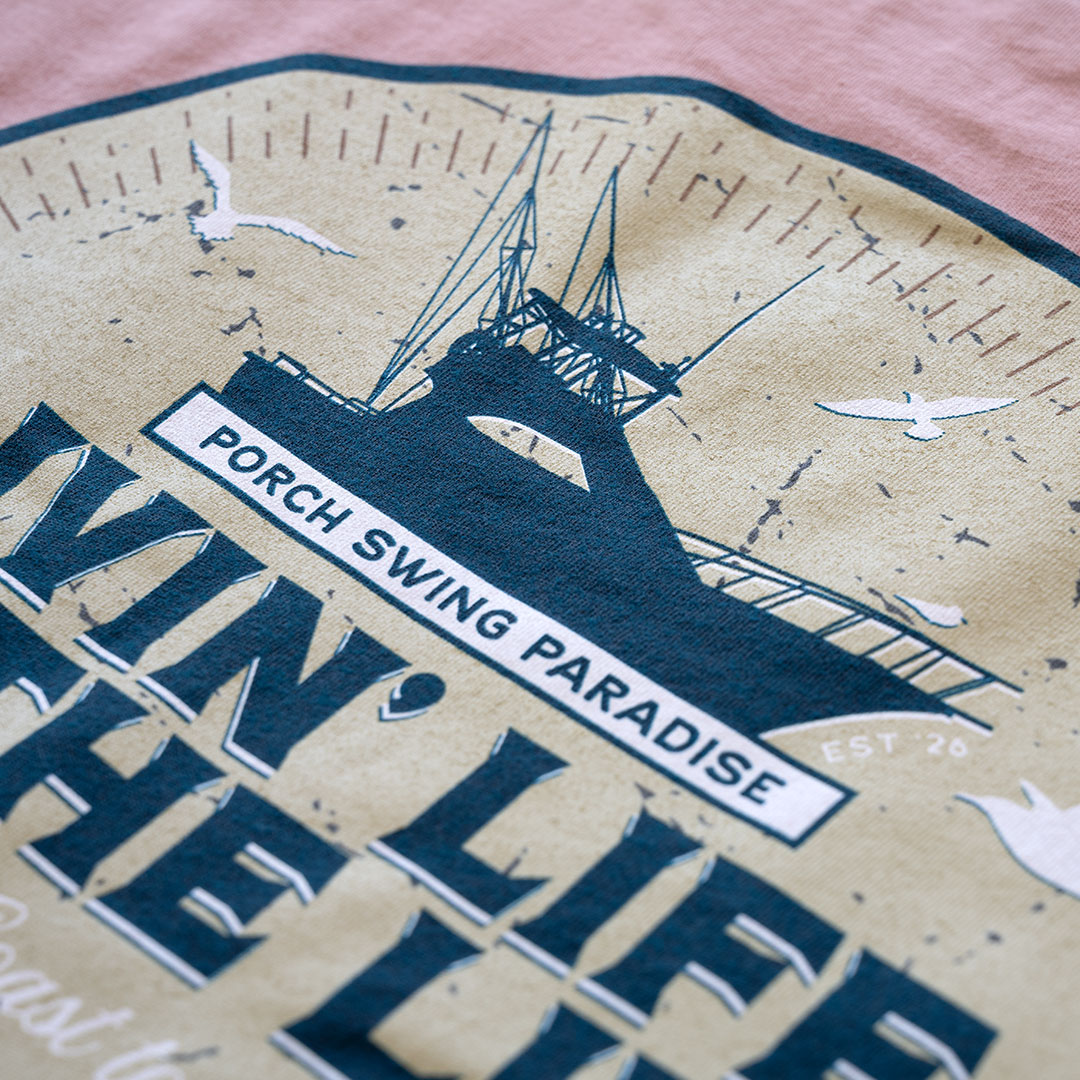 Top view of the back graphic on the Livin' Life on the Line tee in the color dessert pink by Porch Swing Paradise