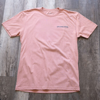 Full front view of the back graphic on the Livin' Life on the Line tee in the color dessert pink by Porch Swing Paradise on a rustic wood backdrop