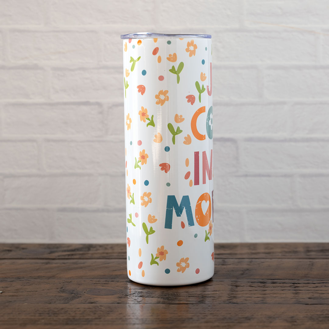 Side view of the Joy Comes in the Morning stainless skinny tumbler against rustic wood backdrop