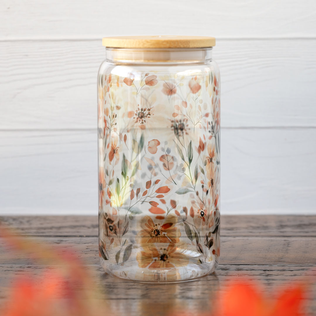 Side view of the Emma K Designs The Meadows glass tumbler in front of greenery and against a rustic wooden backdrop