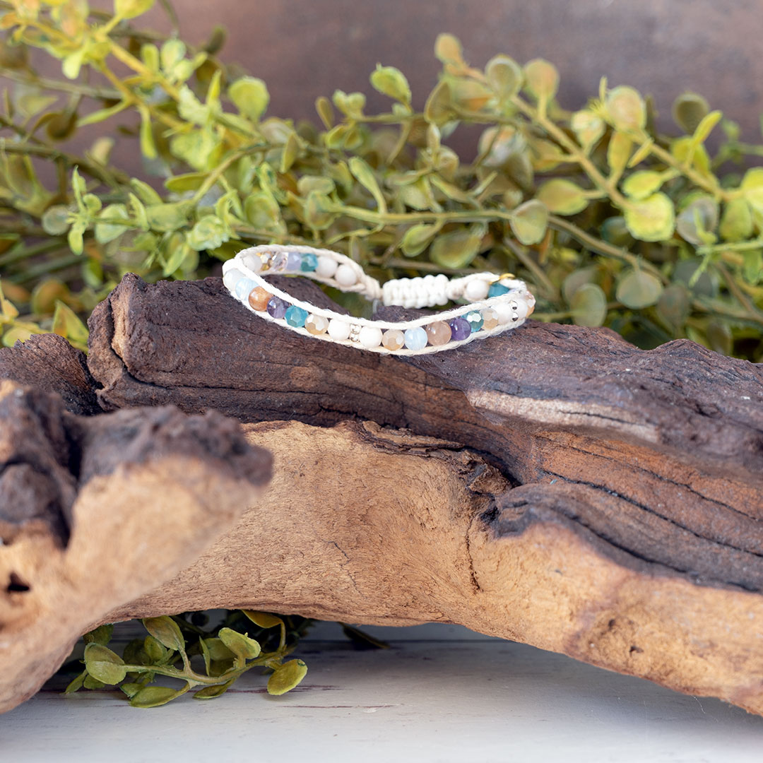 The Coastal Sunset Moonbeam Bracelet on a piece of driftwood with a rustic backdrop
