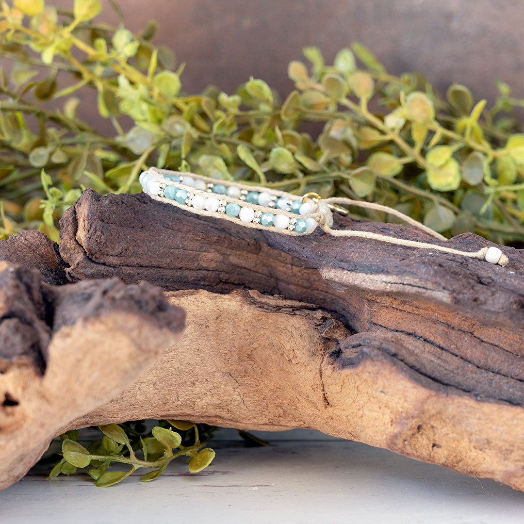 The Pastel Sunrise side view of the Moonbeam Bracelet on a piece of driftwood with a rustic backdrop