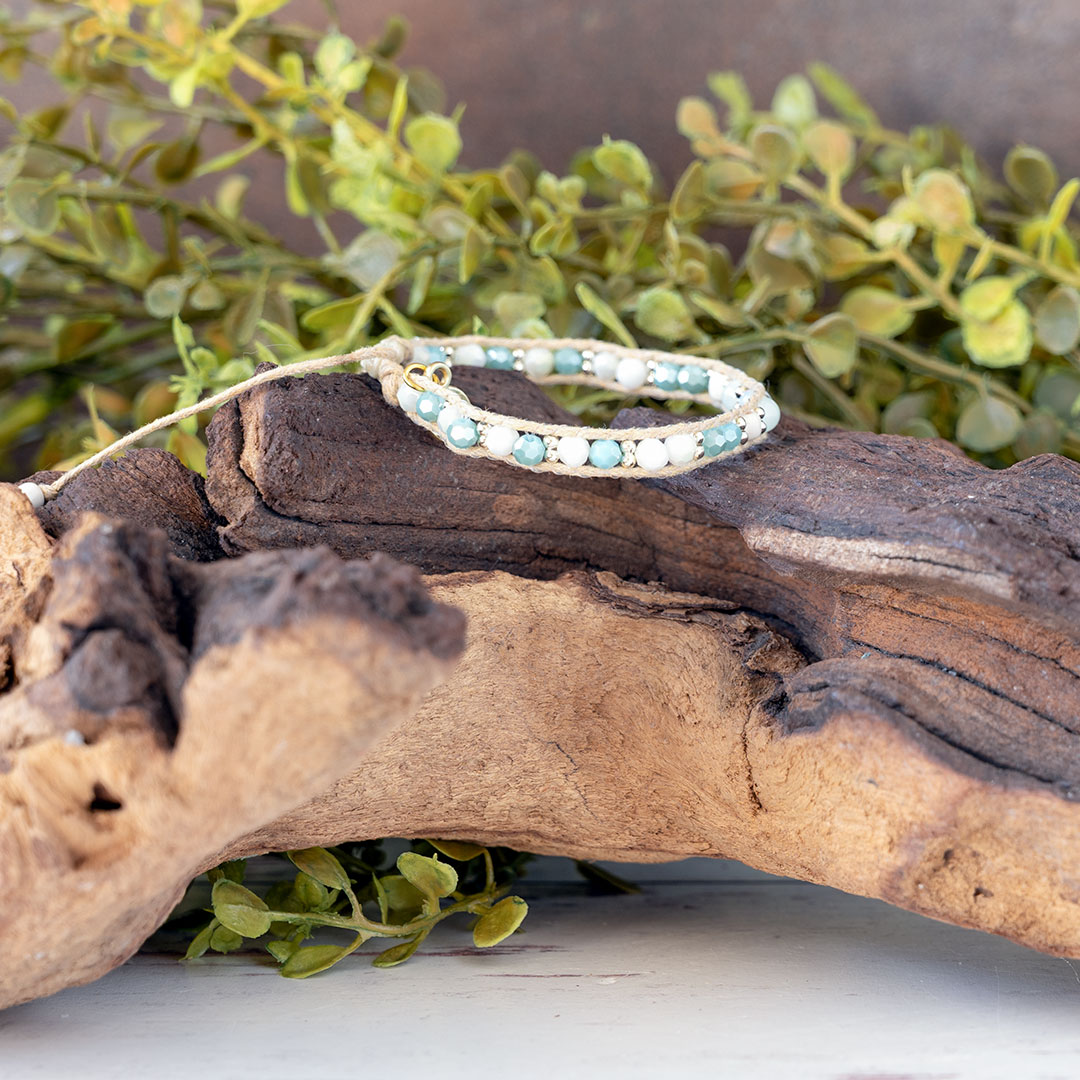 The Pastel Sunrise side view of the Moonbeam Bracelet on a piece of driftwood with a rustic backdrop